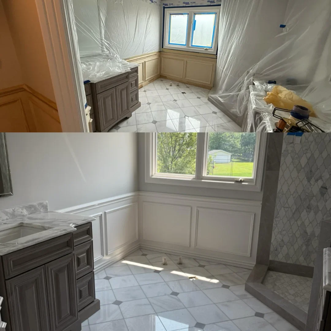 Bathroom with white raised-panel wainscoting, light gray painted walls, gray shaker vanity with marble countertop, and arabesque tile shower
